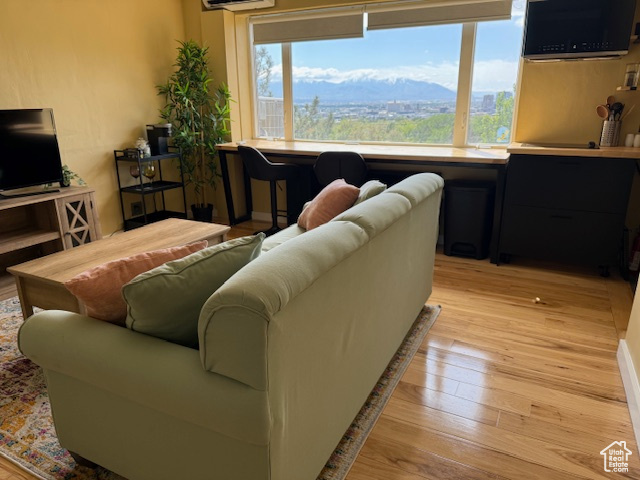 Living room with light wood-style flooring and an AC wall unit