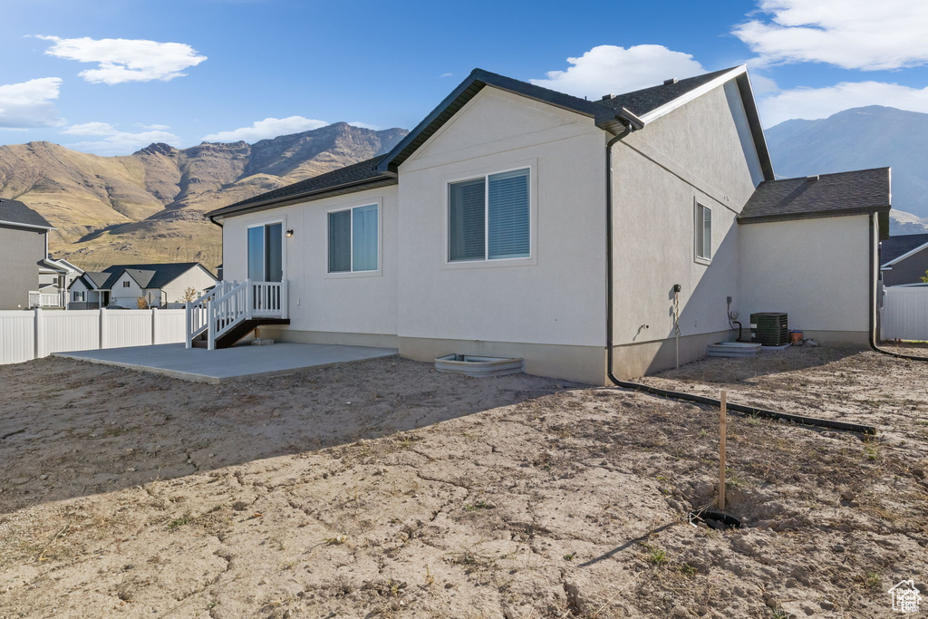 Rear view of house featuring a patio, central AC, fence, and a mountain view