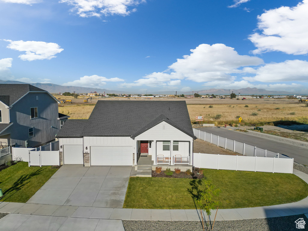 View of front of house featuring covered porch, fence, a mountain view, and a front lawn