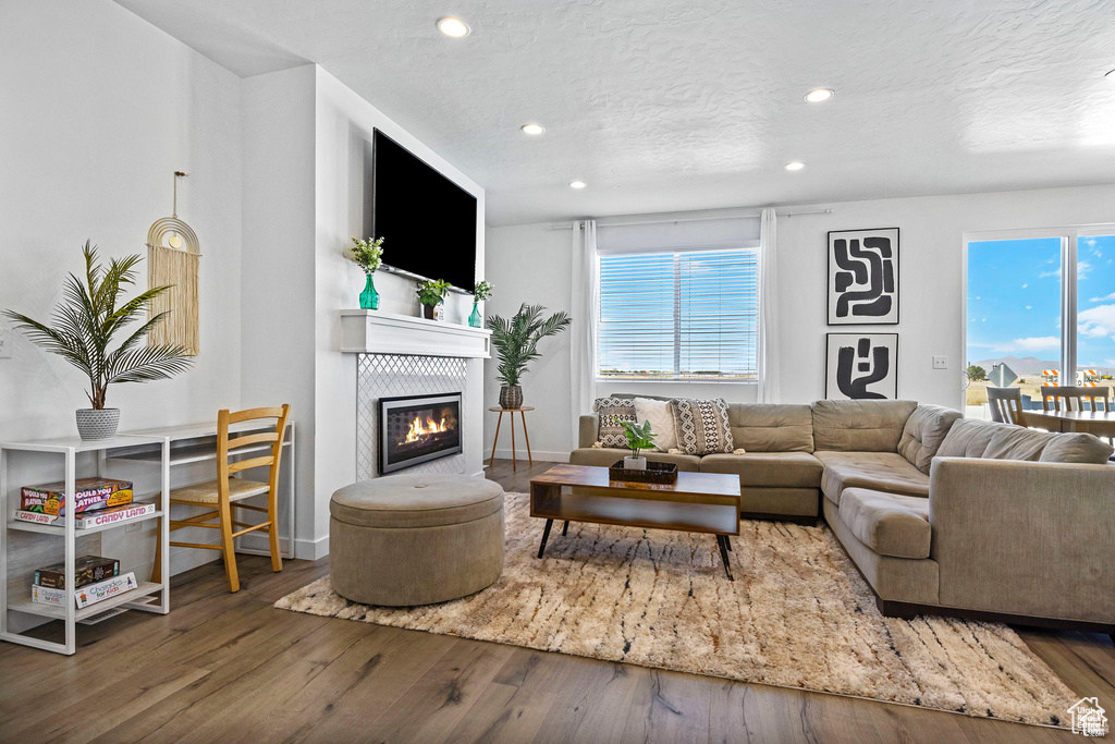 Living area featuring hardwood / wood-style flooring, recessed lighting, a textured ceiling, and a glass covered fireplace