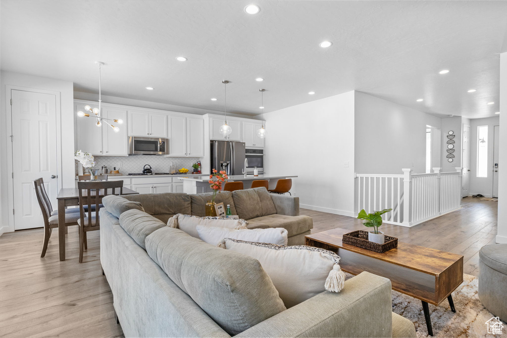 Living area with a notable chandelier, baseboards, light wood-style flooring, and recessed lighting