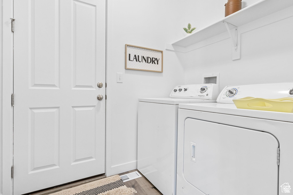 Washroom featuring laundry area, washer and dryer, and wood finished floors