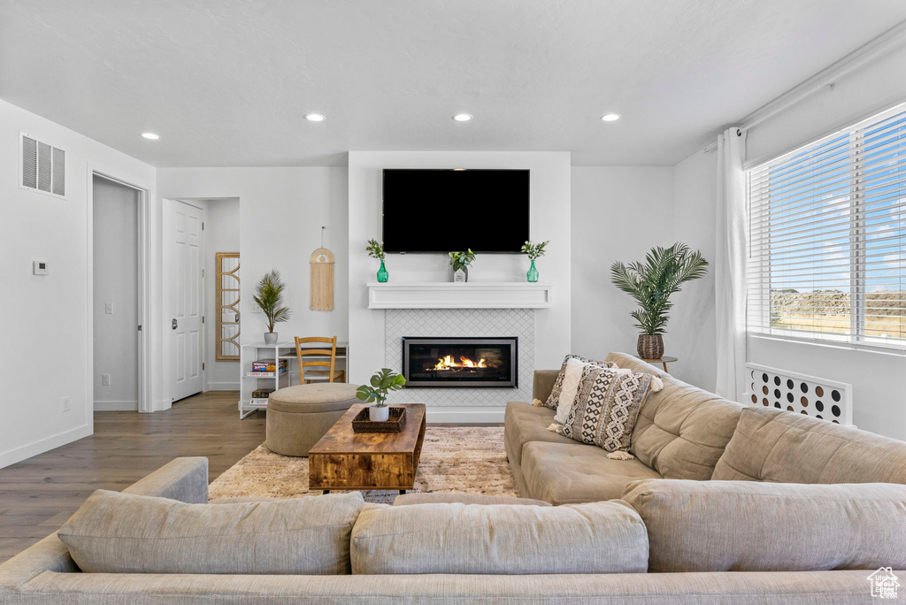 Living area with a fireplace, recessed lighting, visible vents, wood finished floors, and baseboards