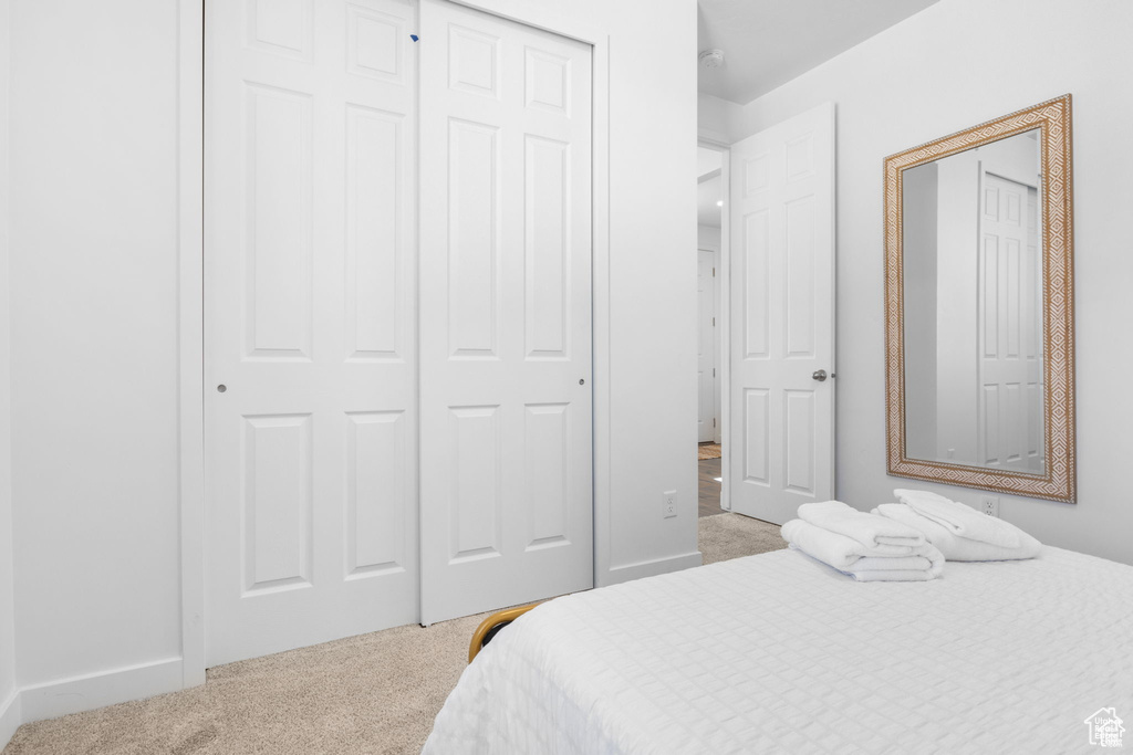 Bedroom featuring baseboards, a closet, and light colored carpet