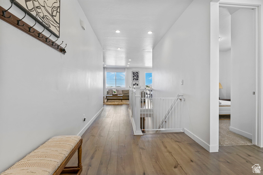 Hallway with baseboards, hardwood / wood-style floors, an upstairs landing, and recessed lighting