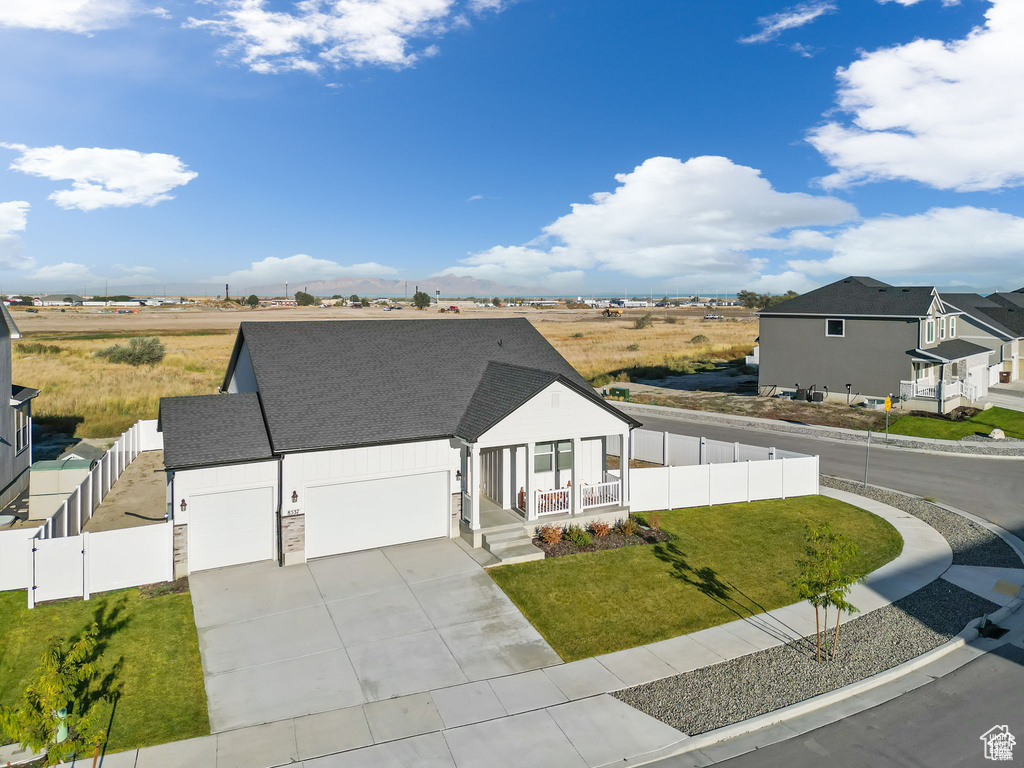 View of front of property featuring a fenced backyard, a porch, concrete driveway, and a front yard