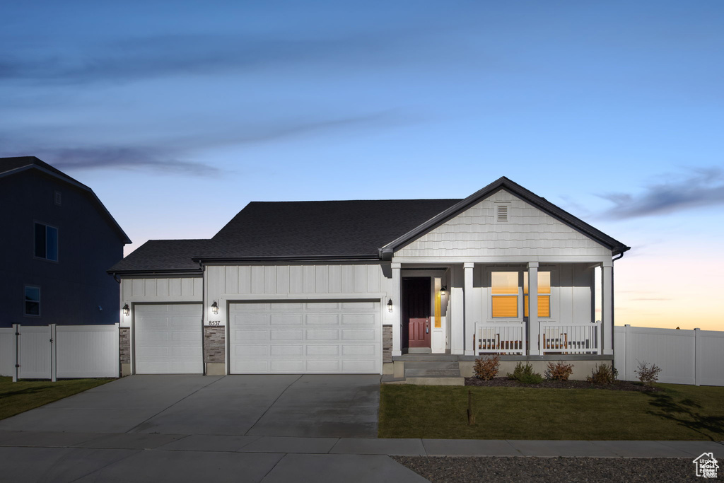 View of front facade featuring covered porch, board and batten siding, an attached garage, and fence