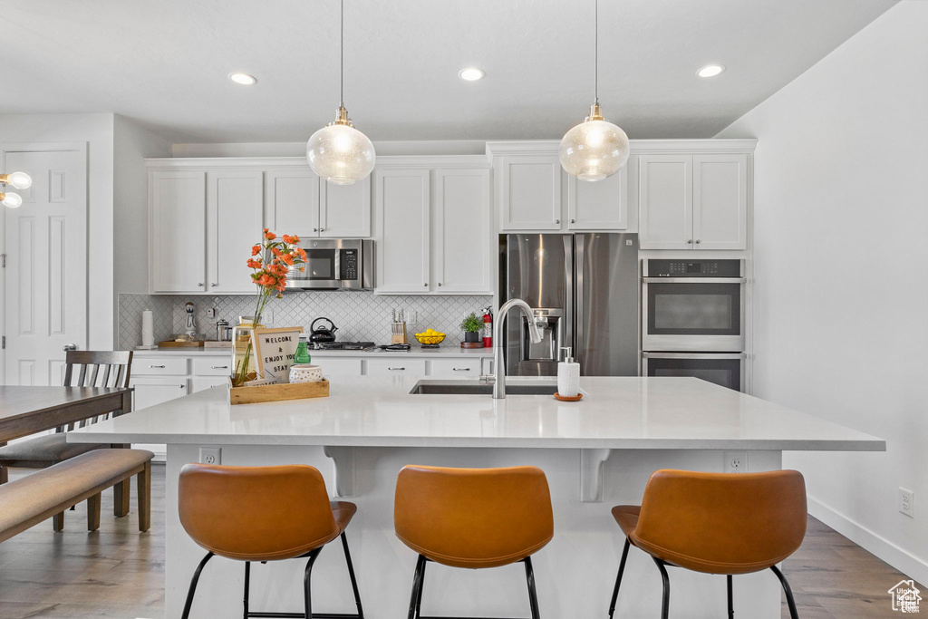 Kitchen with white cabinets, appliances with stainless steel finishes, decorative backsplash, and a sink