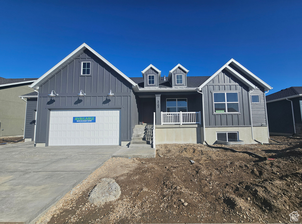 View of front of house with covered porch, concrete driveway, board and batten siding, and an attached garage