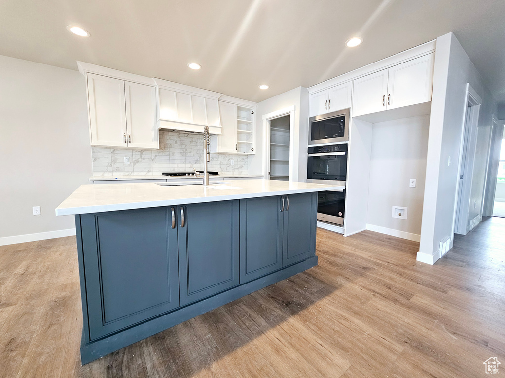 Kitchen with stainless steel appliances, light countertops, and white cabinets
