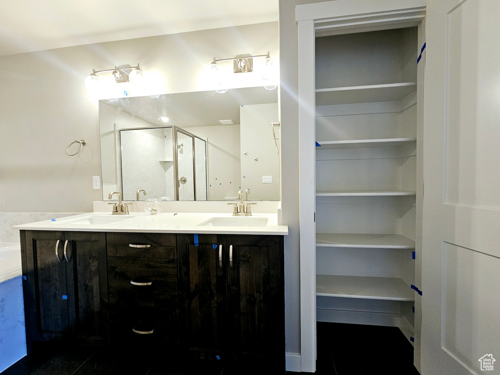 Full bath featuring a sink, a shower stall, and double vanity