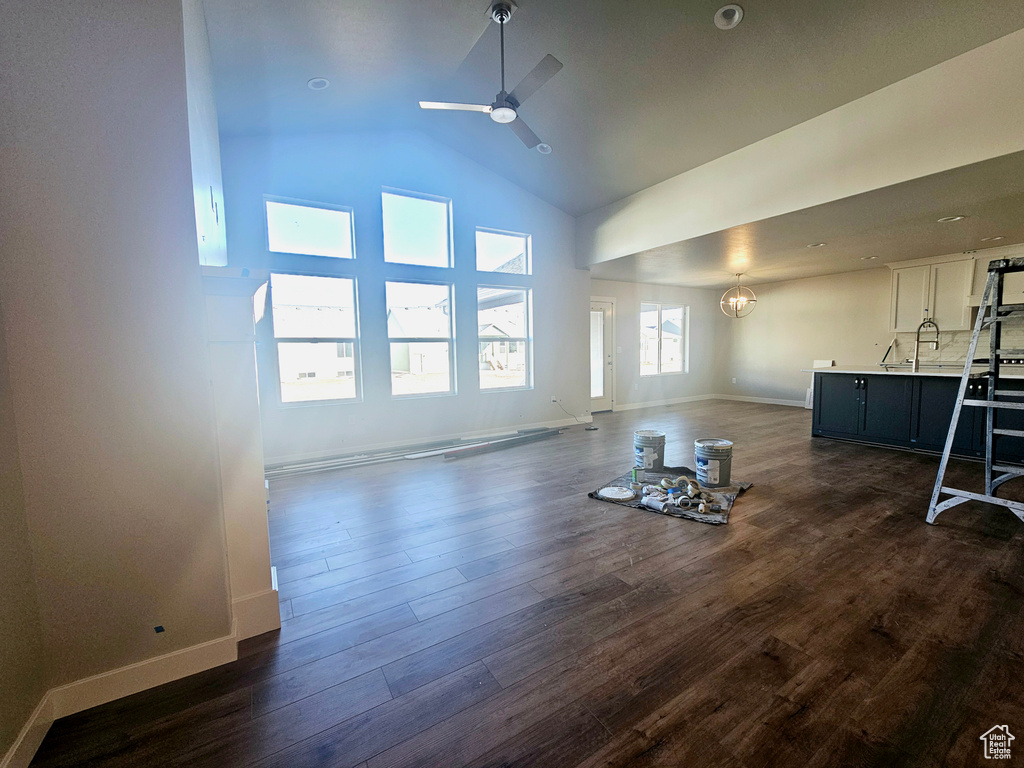 Unfurnished living room with high vaulted ceiling, dark wood-style floors, baseboards, and a ceiling fan