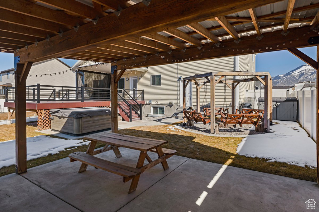 View of patio featuring fence, a mountain view, and a hot tub