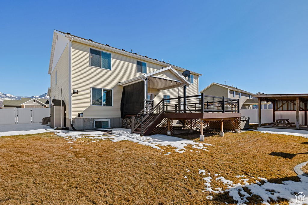 Snow covered property with a deck, fence, stairway, and a patio