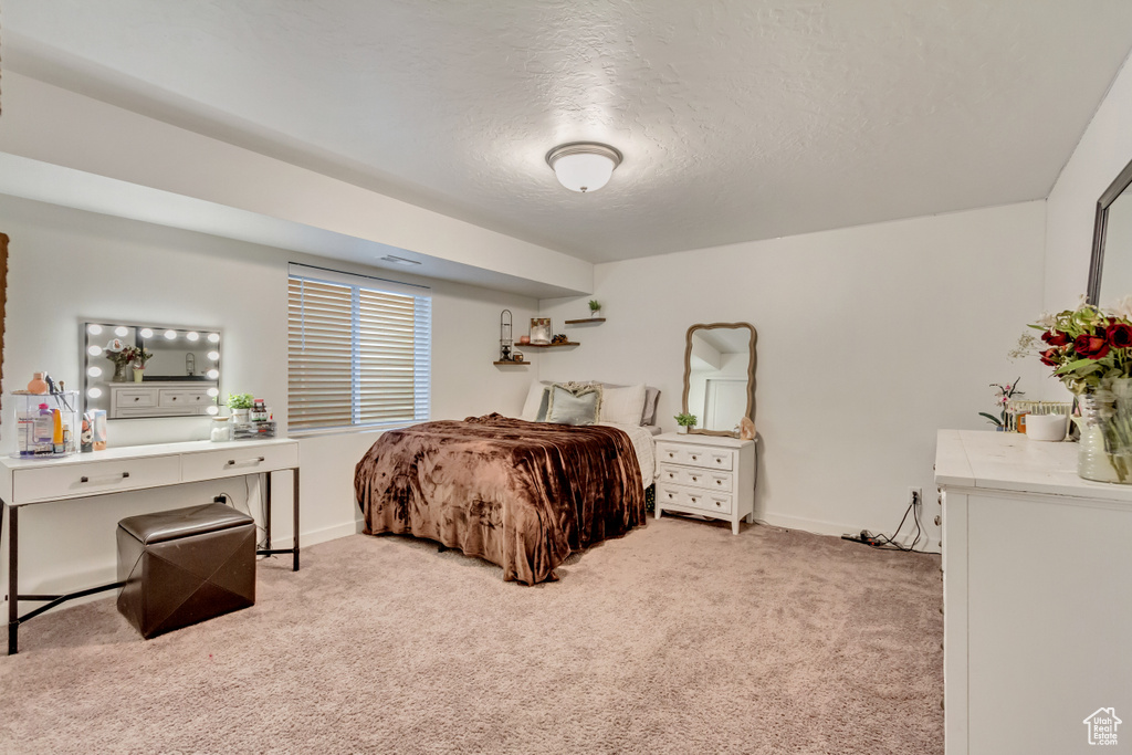 Carpeted bedroom featuring baseboards and a textured ceiling