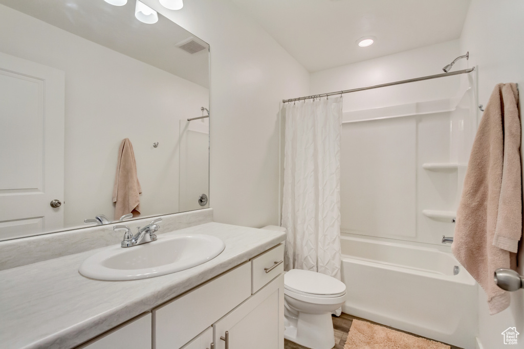 Bathroom with shower / bath combination with curtain, vanity, and toilet