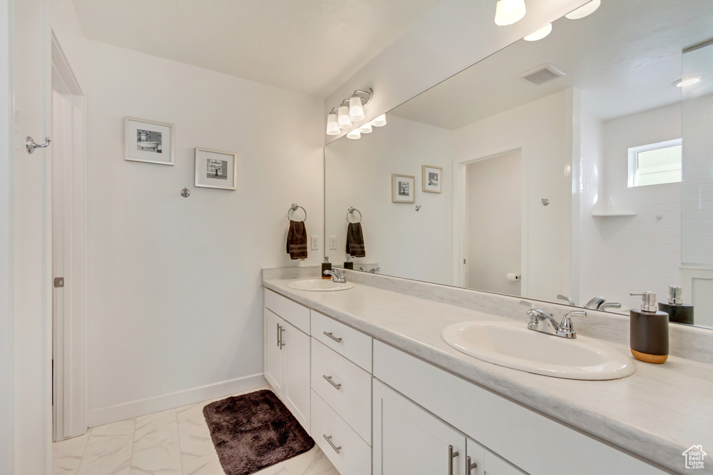 Bathroom with marble finish floor, a sink, baseboards, and double vanity