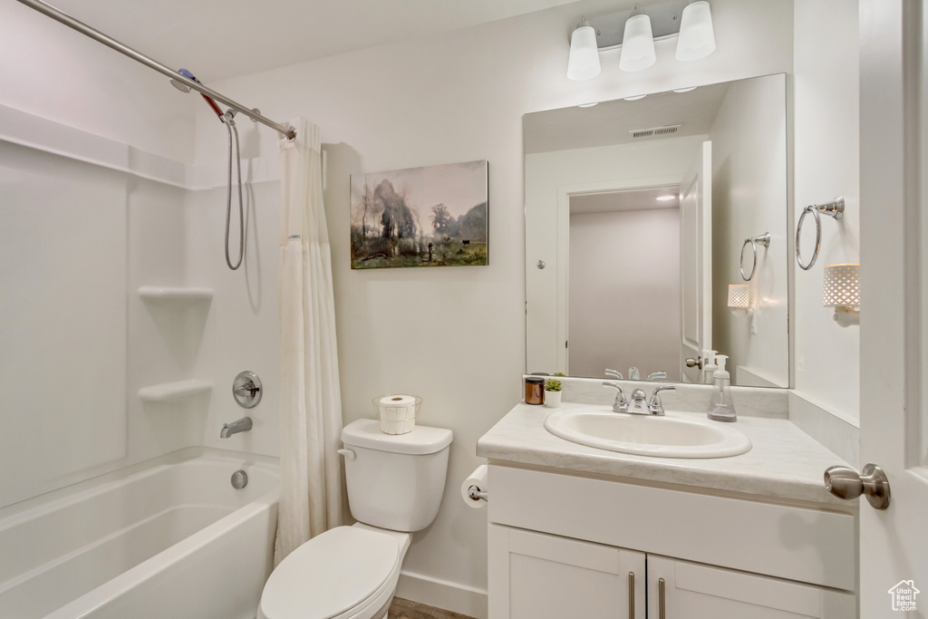 Bathroom featuring shower / bathtub combination with curtain, visible vents, vanity, and toilet