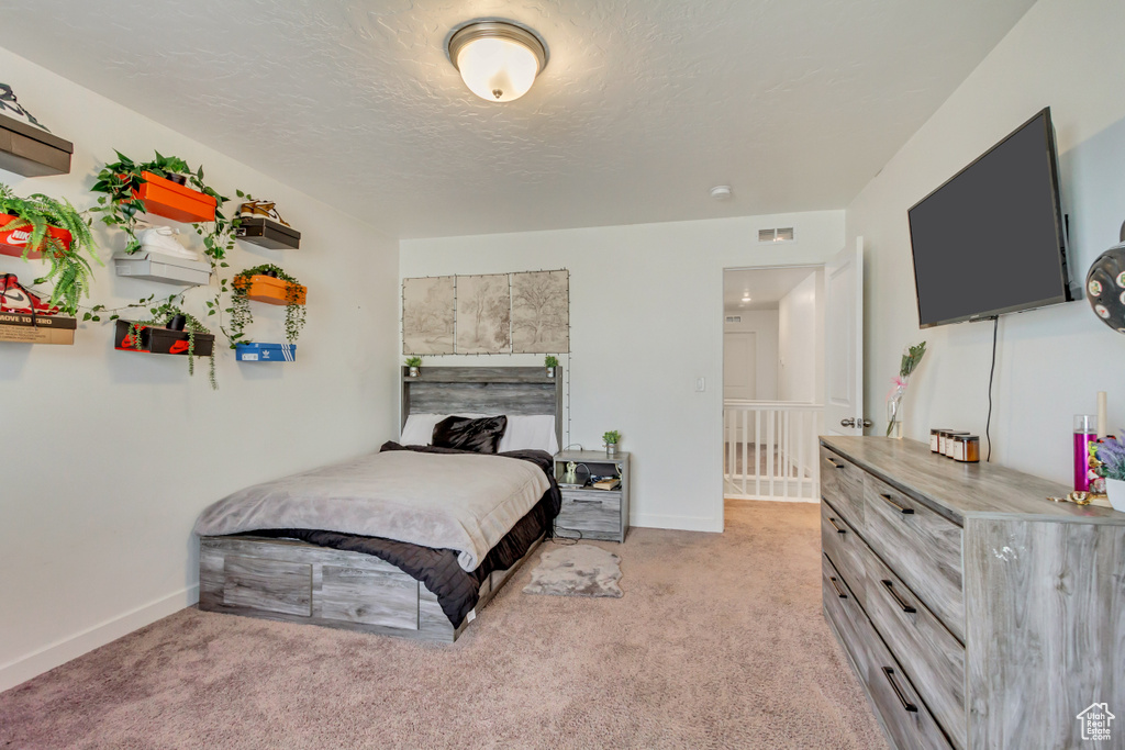 Bedroom with baseboards, visible vents, a textured ceiling, and light colored carpet