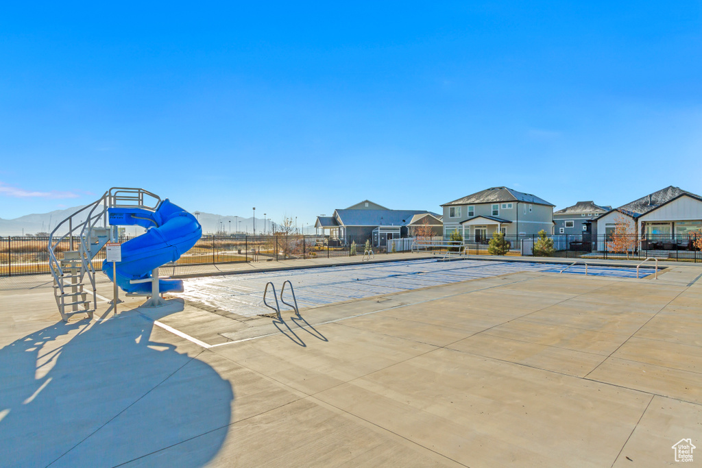 View of swimming pool featuring a tennis court and fence