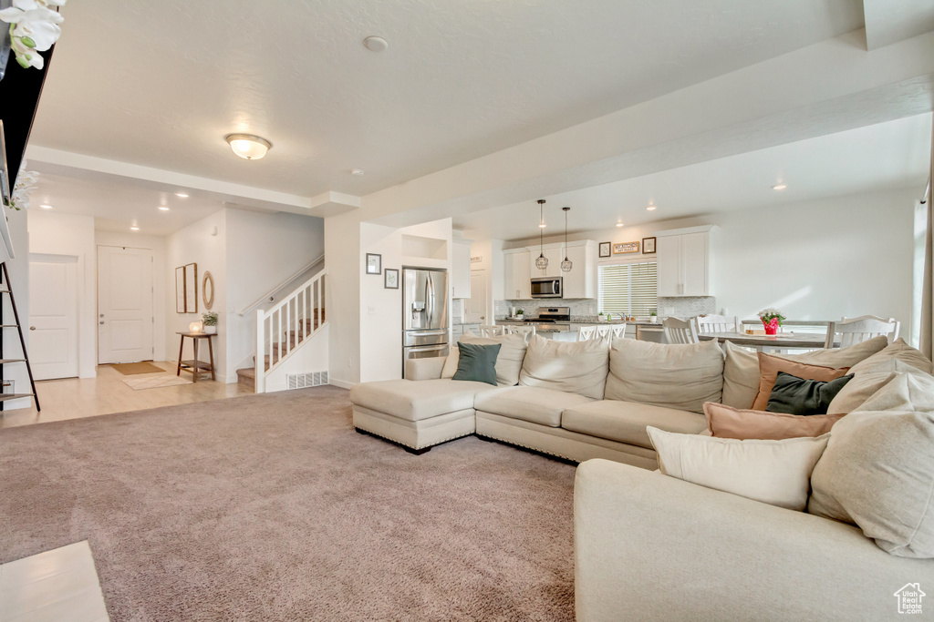 Living area featuring recessed lighting, light colored carpet, and stairs