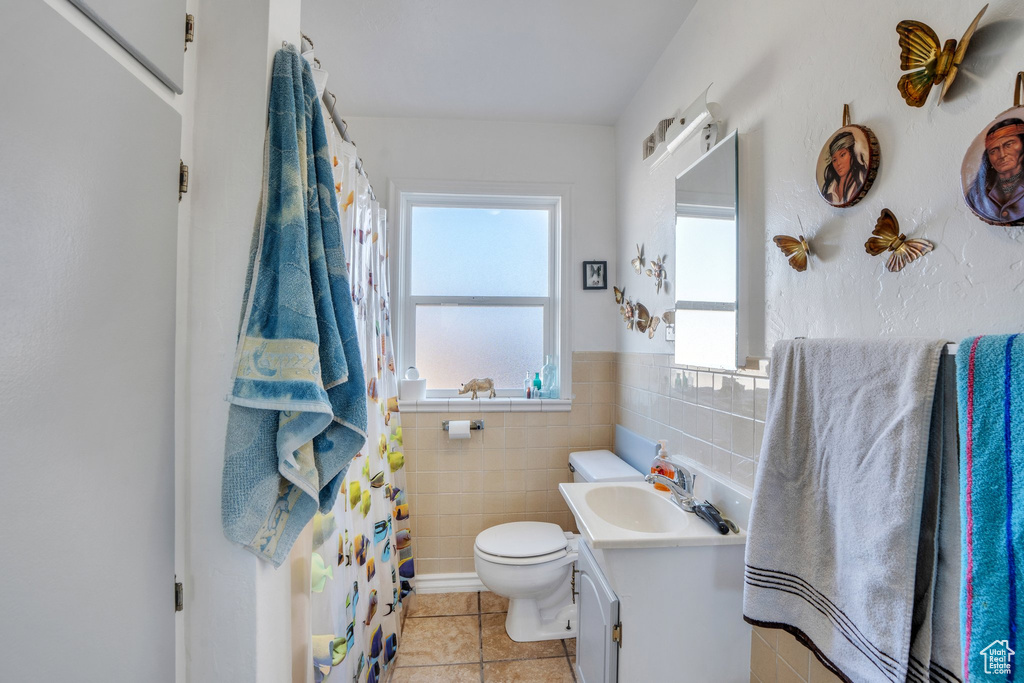 Bathroom featuring tile walls, curtained shower, toilet, vanity, and tile patterned flooring