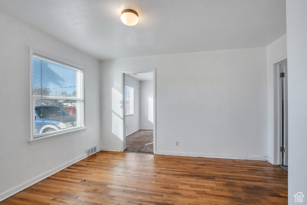 Spare room with baseboards, visible vents, and wood finished floors