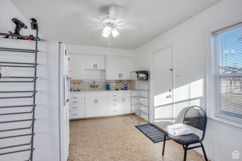 Kitchen featuring tasteful backsplash, light countertops, freestanding refrigerator, white cabinetry, and ceiling fan