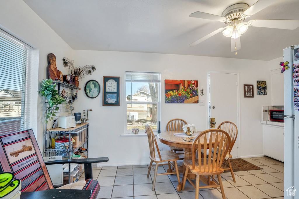 Dining room with light tile patterned floors, ceiling fan, and baseboards