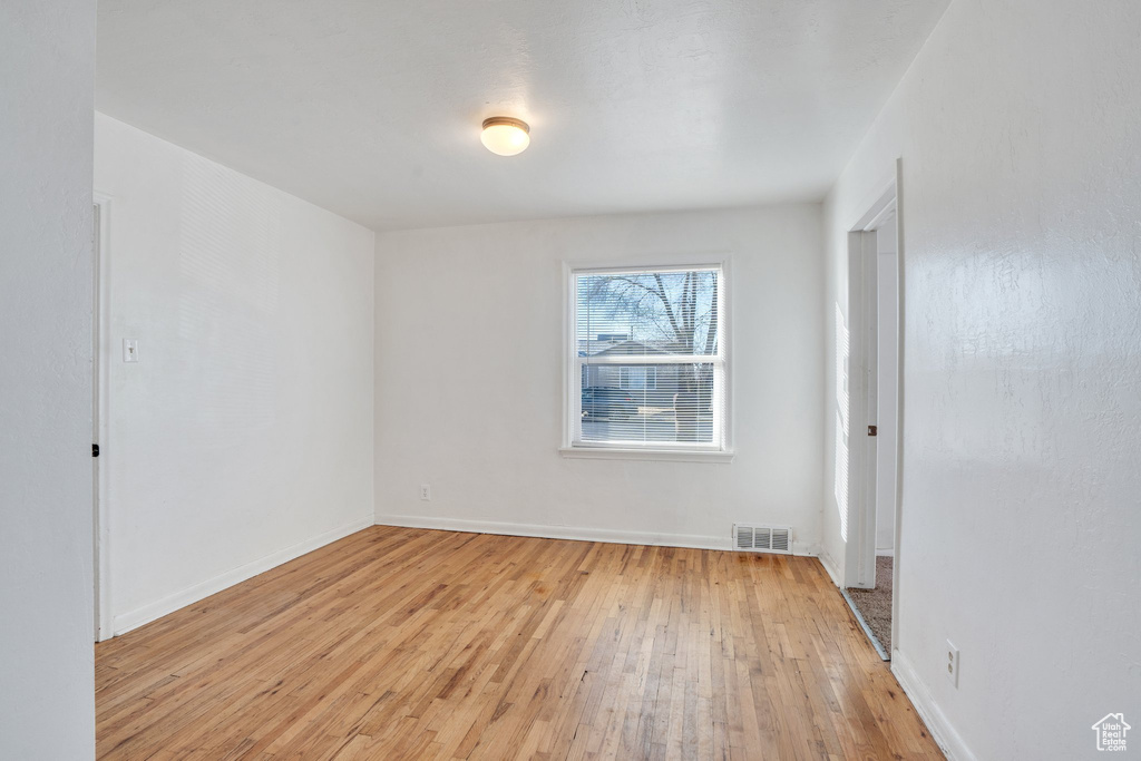 Spare room with baseboards, visible vents, and light wood finished floors