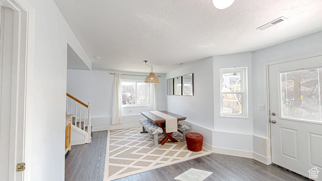 Foyer entrance with stairway, baseboards, visible vents, and wood finished floors