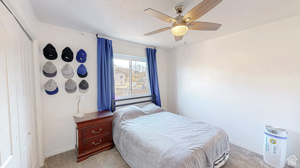 Bedroom with a ceiling fan, a closet, light carpet, and baseboards