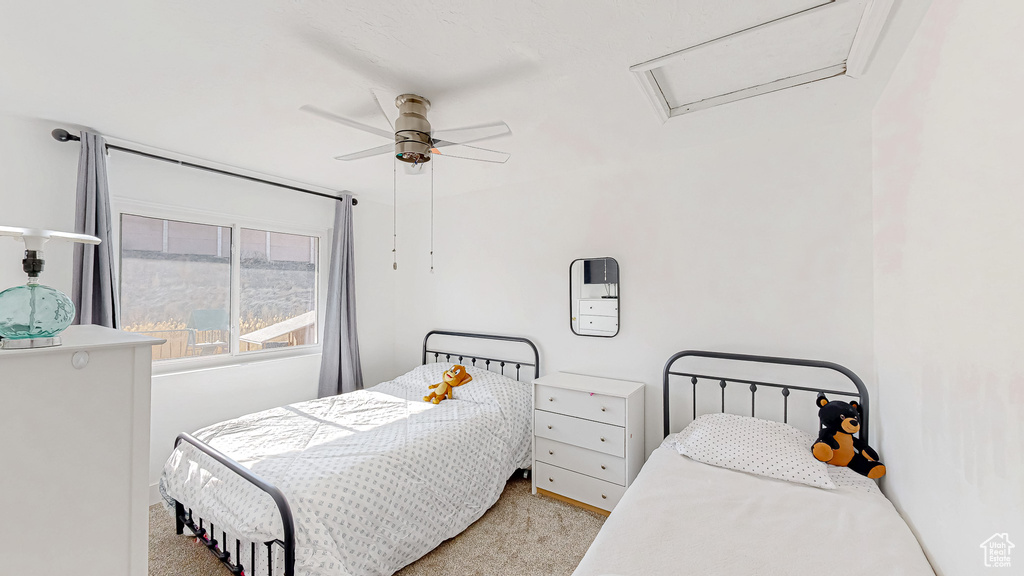 Carpeted bedroom with attic access and a ceiling fan