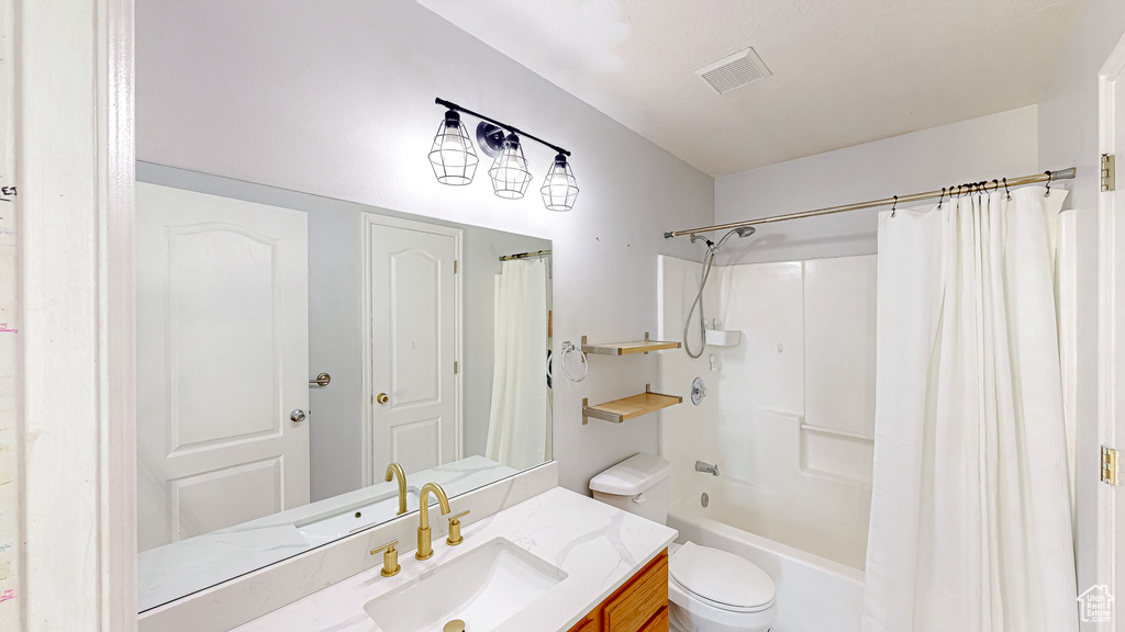 Bathroom with visible vents, vanity, toilet, and shower / bath combo with shower curtain