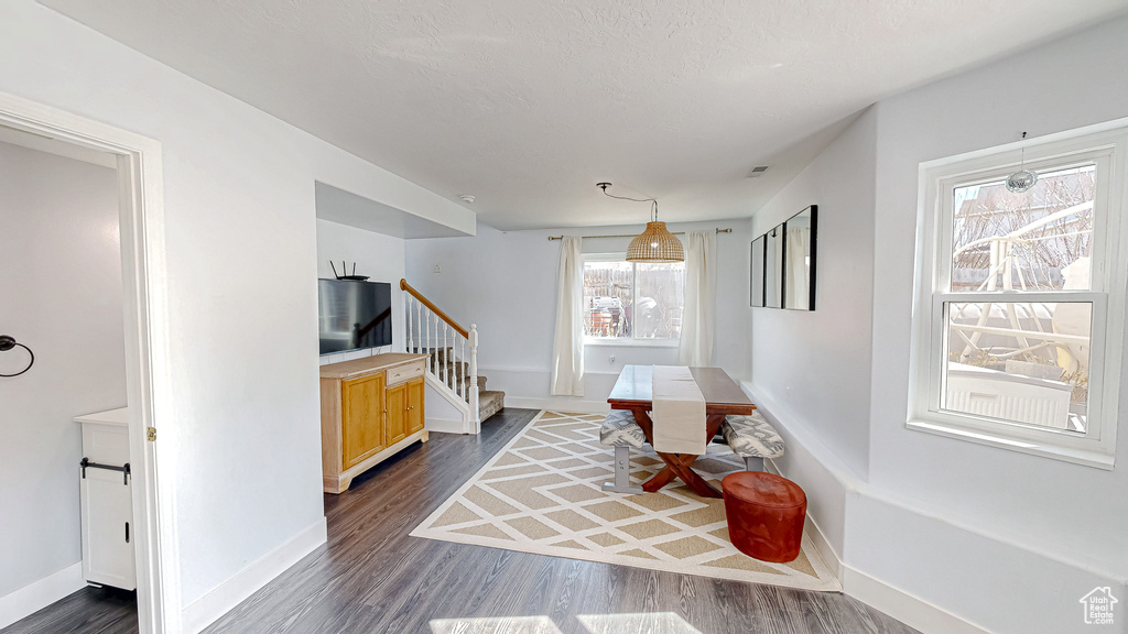 Dining room featuring dark wood-style floors, stairs, and baseboards