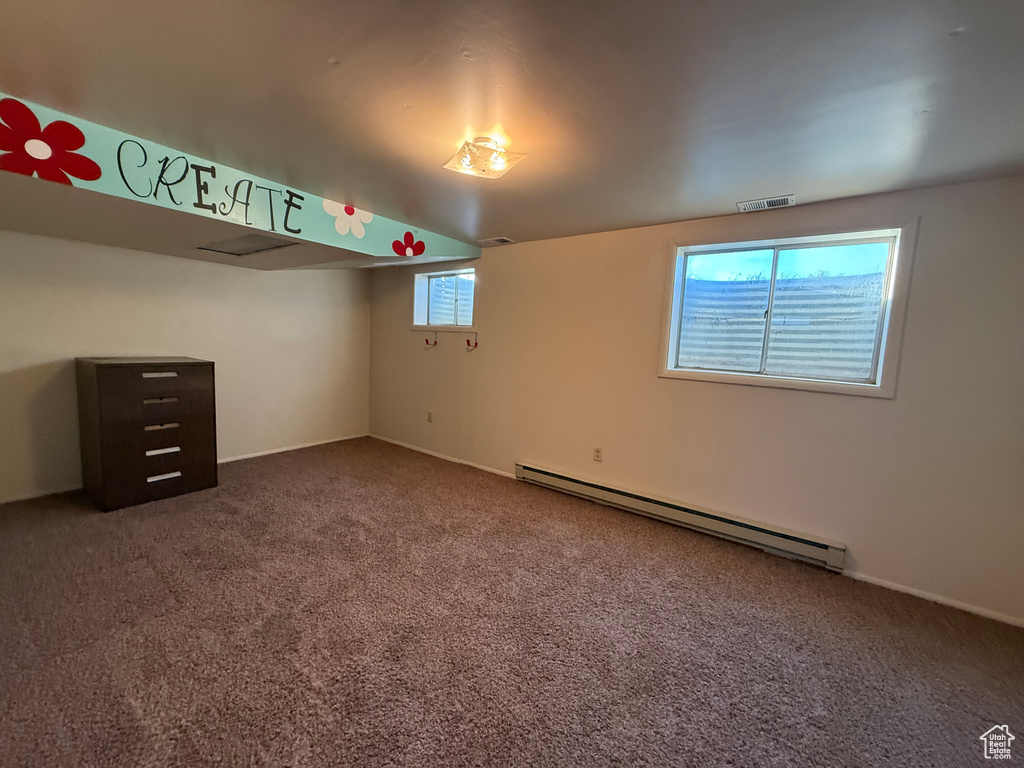 Carpeted empty room featuring a baseboard radiator and baseboards