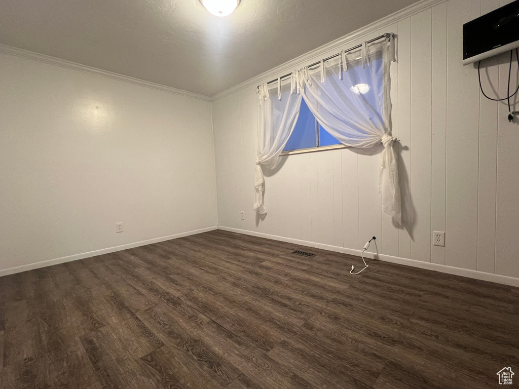 Spare room with baseboards, crown molding, visible vents, and dark wood-type flooring