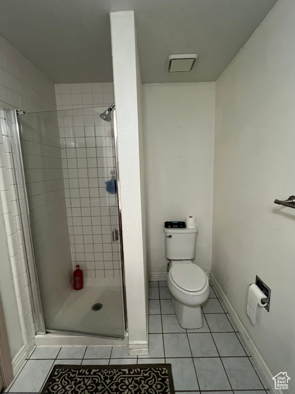 Bathroom with a stall shower, tile patterned flooring, baseboards, and toilet