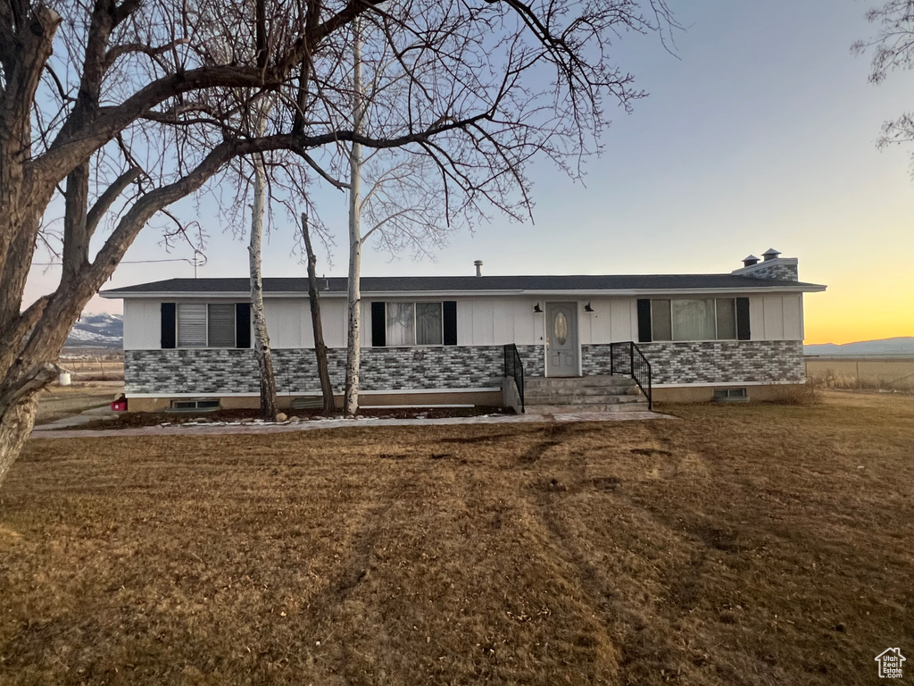 View of front of property featuring board and batten siding, stone siding, and a front lawn