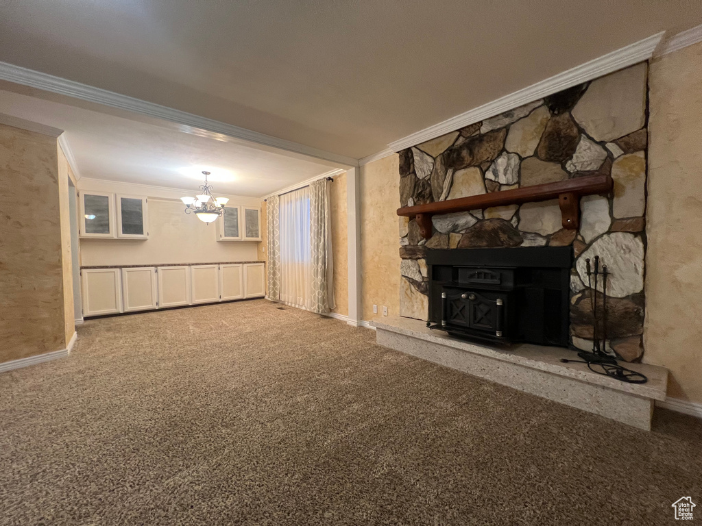 Unfurnished living room featuring baseboards, ornamental molding, carpet flooring, and an inviting chandelier