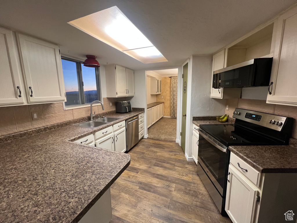 Kitchen featuring dark countertops, backsplash, stainless steel appliances, and a sink