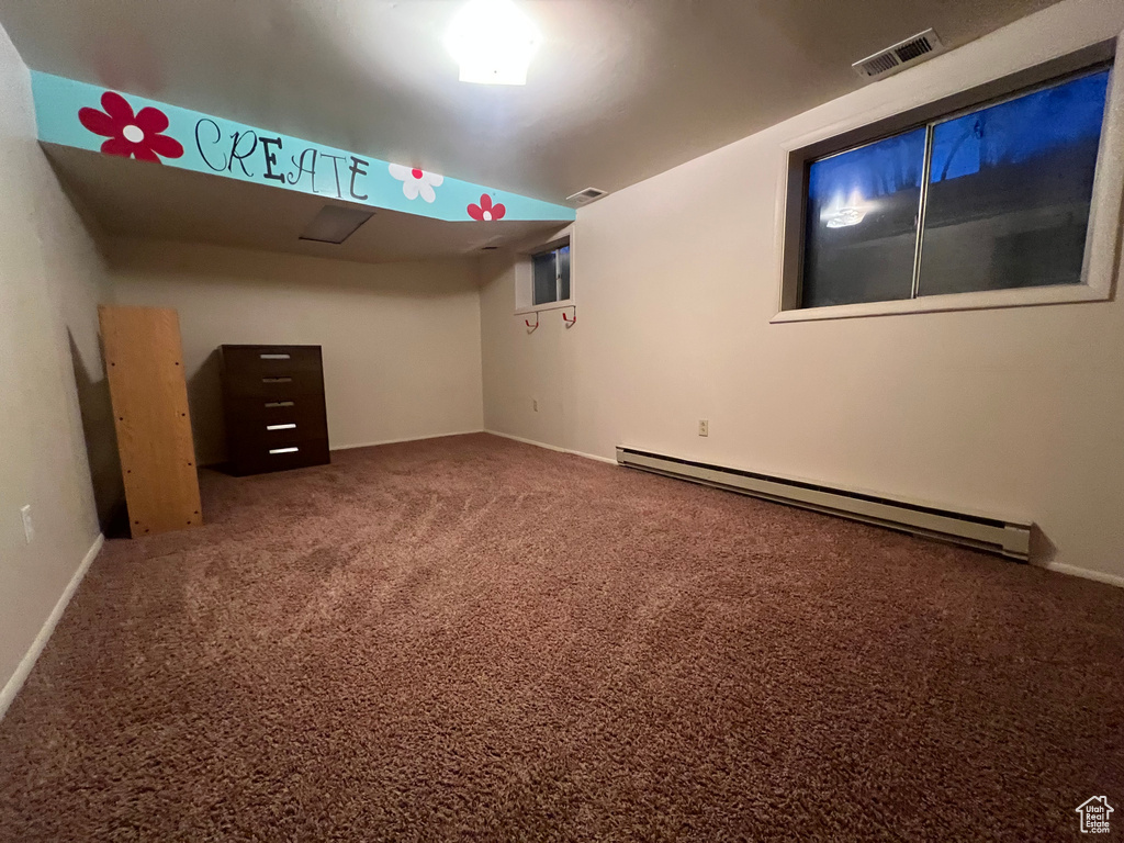 Spare room with carpet flooring, visible vents, and baseboard heating