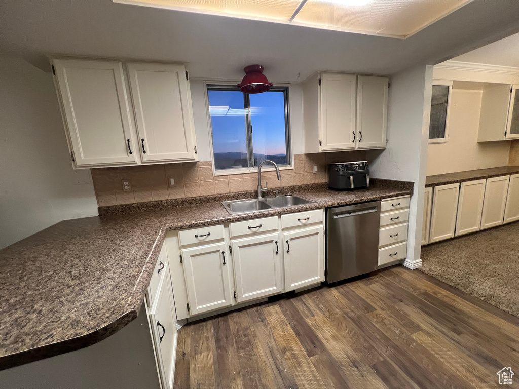 Kitchen featuring white cabinets, dishwasher, dark countertops, dark wood-style floors, and a sink