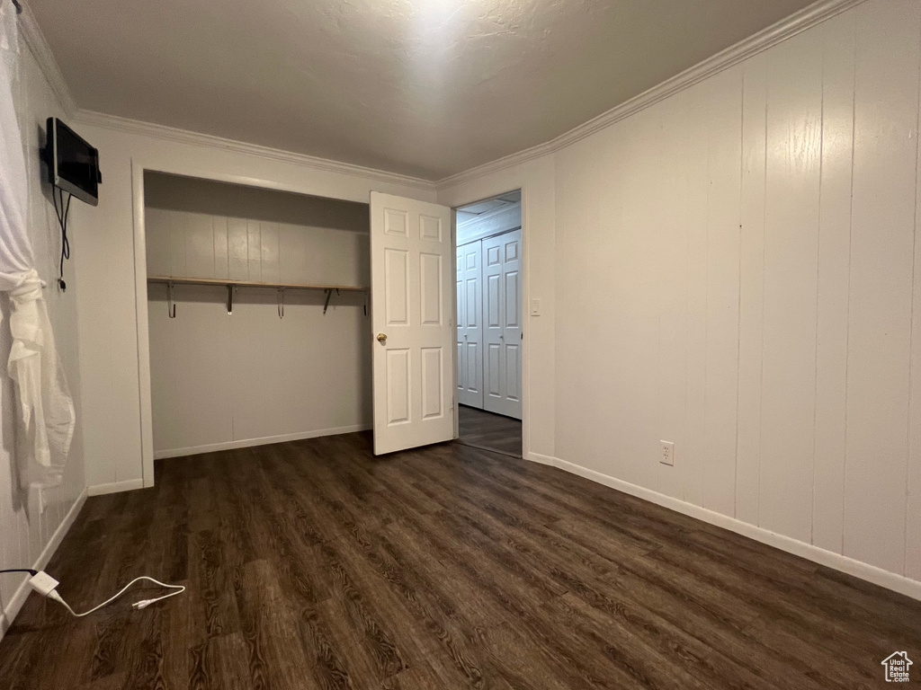 Unfurnished bedroom with baseboards, ornamental molding, and dark wood-style flooring