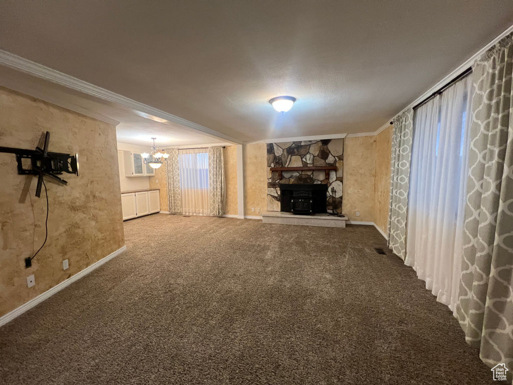 Below grade area with a notable chandelier, a fireplace, carpet flooring, and crown molding