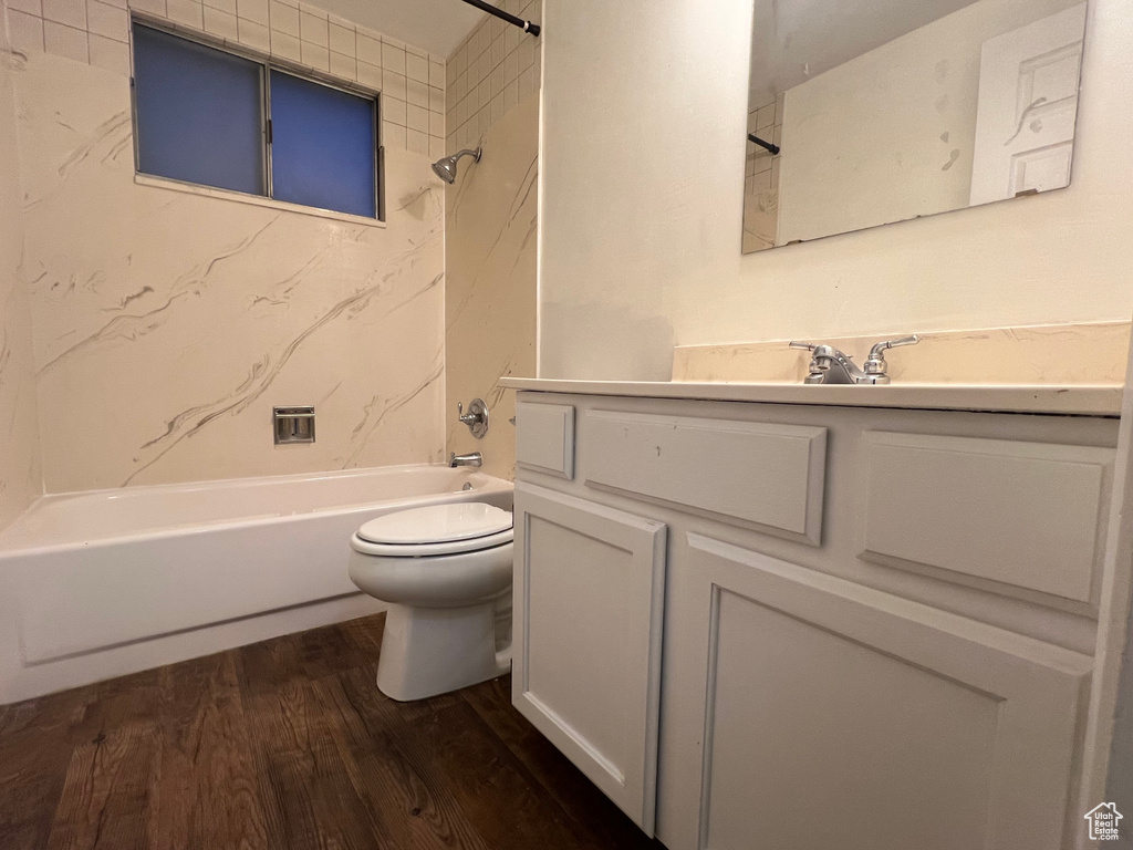 Bathroom featuring toilet, shower / bath combination, wood finished floors, and vanity