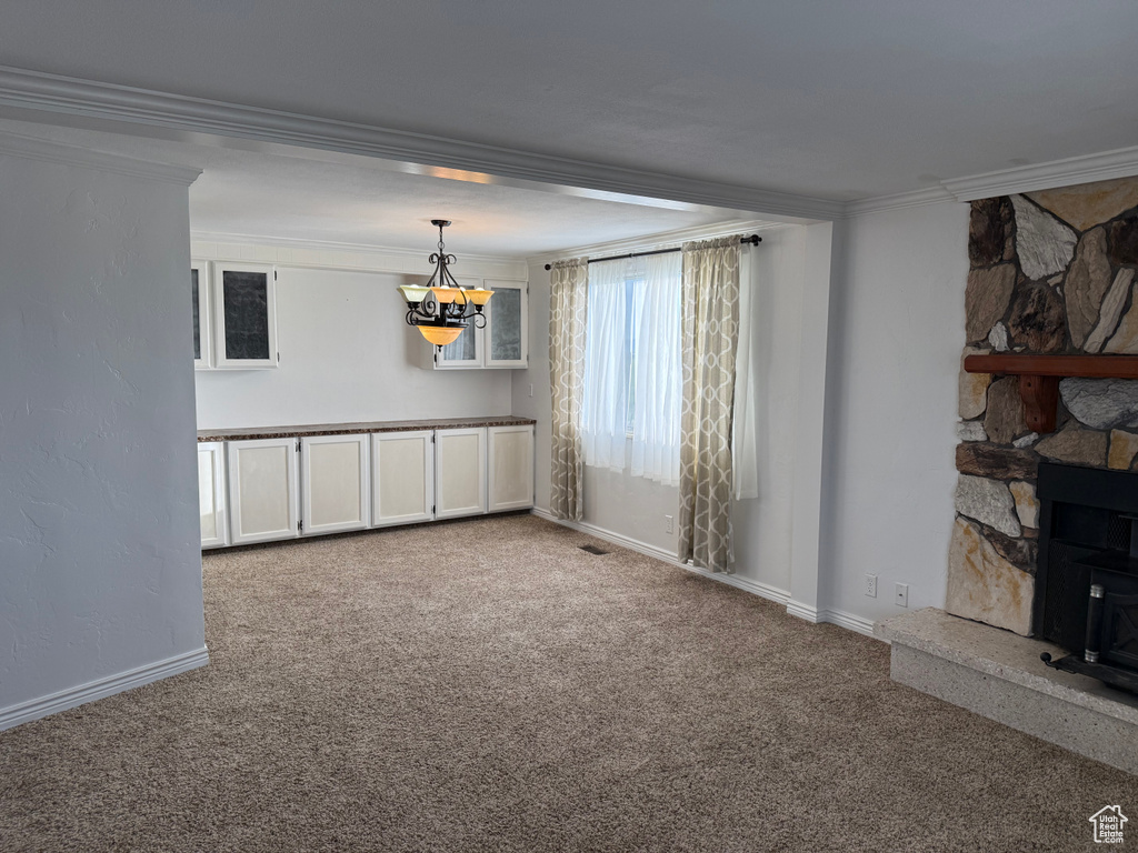 Unfurnished room featuring a chandelier, carpet floors, crown molding, and baseboards