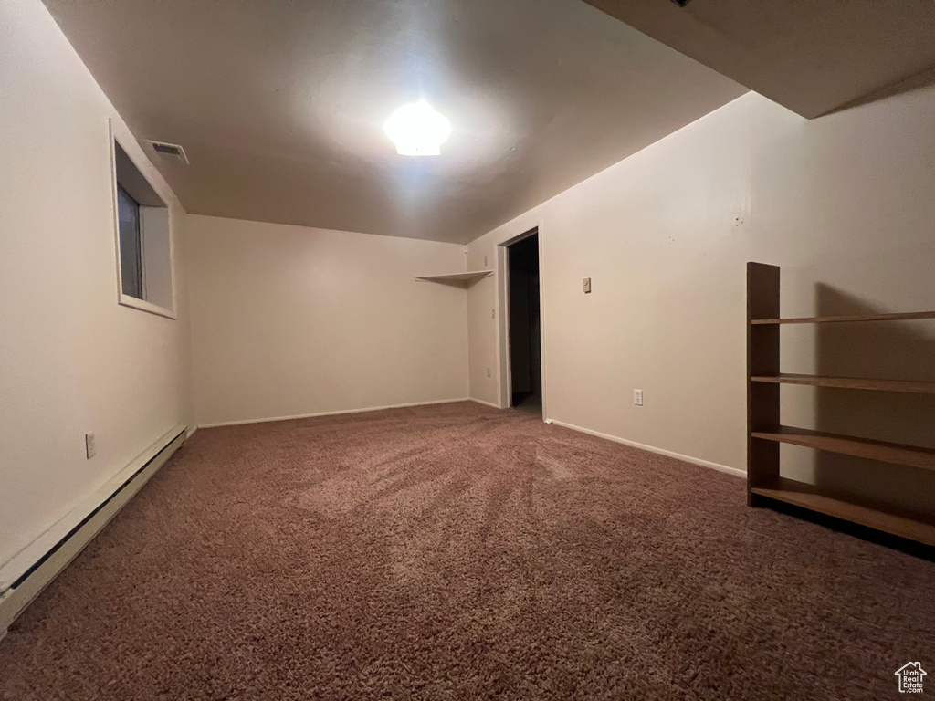 Carpeted empty room featuring a baseboard radiator, visible vents, and baseboards