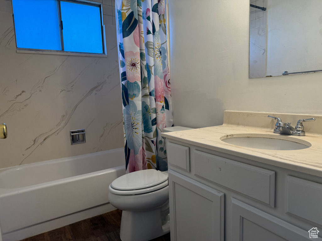 Bathroom with vanity, toilet, shower / bath combo, and wood finished floors