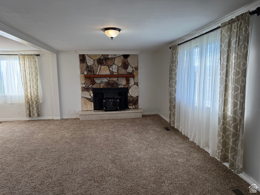 Unfurnished living room featuring carpet flooring, crown molding, baseboards, and a fireplace